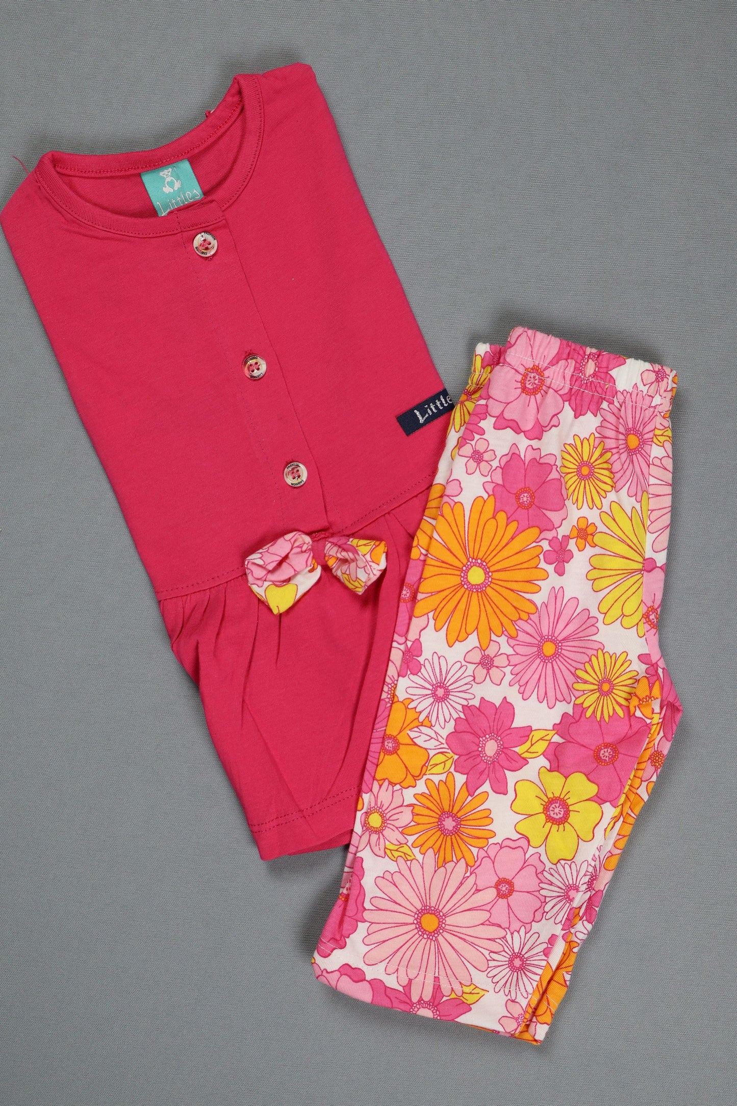 Pink baby outfit with floral pants on a gray background