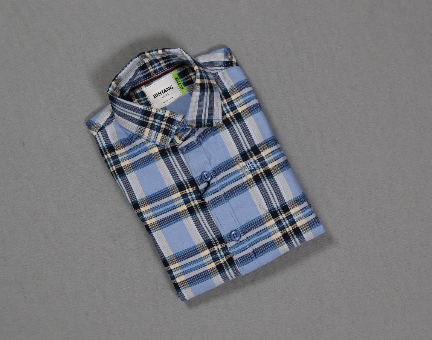 Folded blue and white checkered cotton kids shirt on gray background