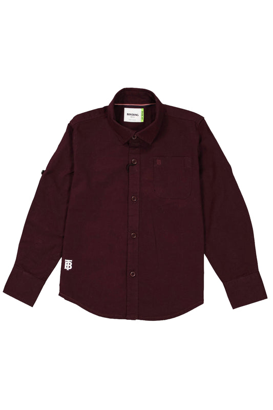 A children's full-sleeve casual shirt in a deep maroon or burgundy color. The shirt features a classic spread collar, a single chest pocket with a small white brand tag at the bottom hem, and matching tonal buttons. The sleeves include roll-up tabs for a customizable look. The garment is shown as a flat lay against a neutral grey background.