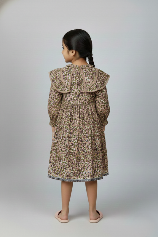 Child wearing a floral dress with a hood on a plain background