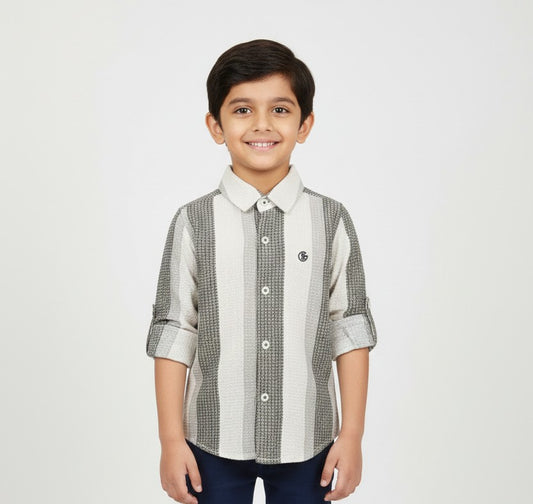 A young boy smiling in a professional studio setting, modeling a Fyst brand button-down shirt featuring wide vertical stripes in white, light grey, and a textured charcoal grey