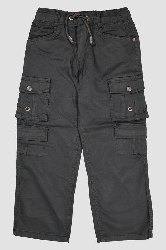 A pair of children's utility cargo pants in a deep Black. The pants feature a comfortable elastic waistband with a matching drawstring, two standard side pockets, and two large multi-compartment cargo pockets on the legs with secure button closures. They are shown as a flat lay against a neutral grey background.
