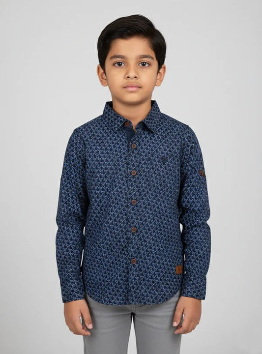 A young boy modeling a Fyst brand dark navy blue button-down shirt featuring a dense, repeating geometric diamond pattern. The shirt has contrasting brown buttons, a structured collar, and long sleeves, presented in a professional studio shot against a light grey background.