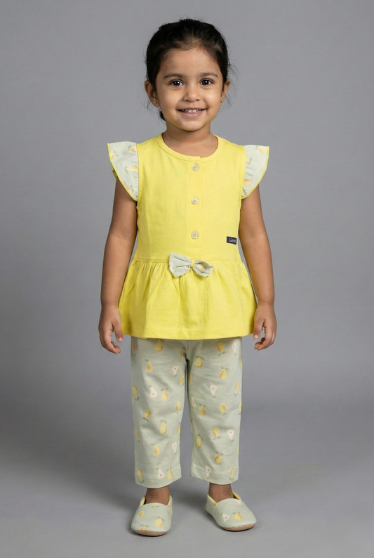 A girls' two-piece summer set featuring a bright yellow sleeveless top and matching light green pants. The top has a button-down front, a flared peplum waist, and a small decorative bow. The flutter sleeves and the bow contrast with the yellow body, featuring a light green fabric with a pattern of yellow pears. The accompanying capri pants are light sage green and covered in an all-over print of yellow pears