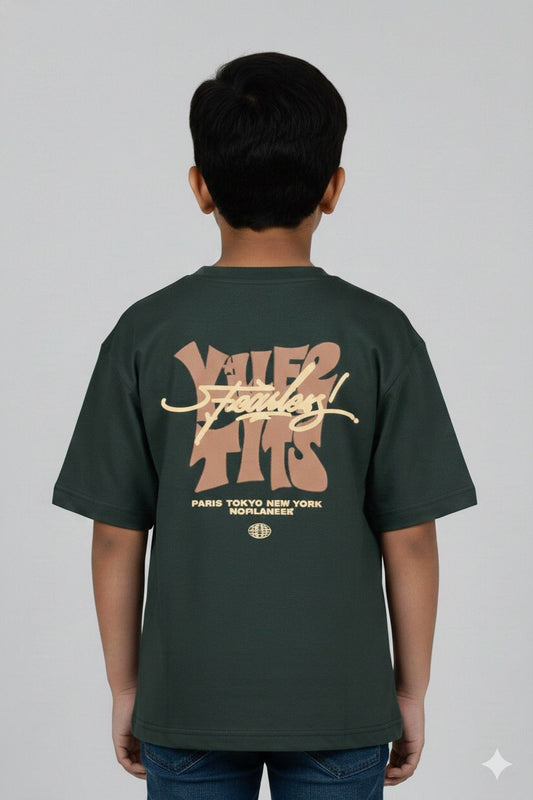 A young boy modeling a dark green oversized t-shirt. The front features a small neutral-toned graphic on the chest, while the back displays a large, intricate streetwear-style typography design. He is posing against a plain grey background.