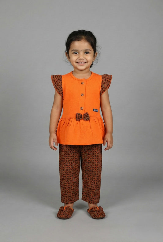 Flat lay of a two-piece girls' outfit featuring a folded orange button-down top and matching brown capri pants with an orange circular print.