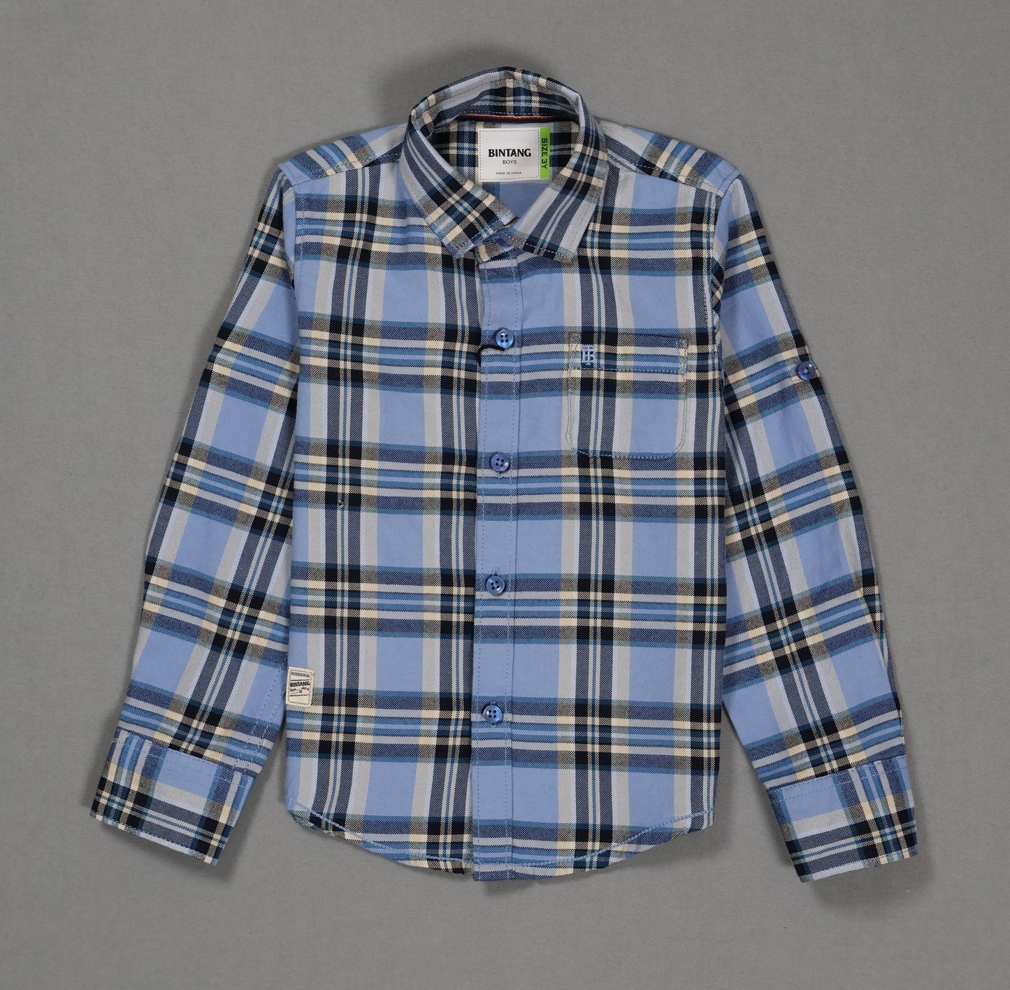 Blue and black plaid cotton kids shirt with long sleeves and front pocket on grey background