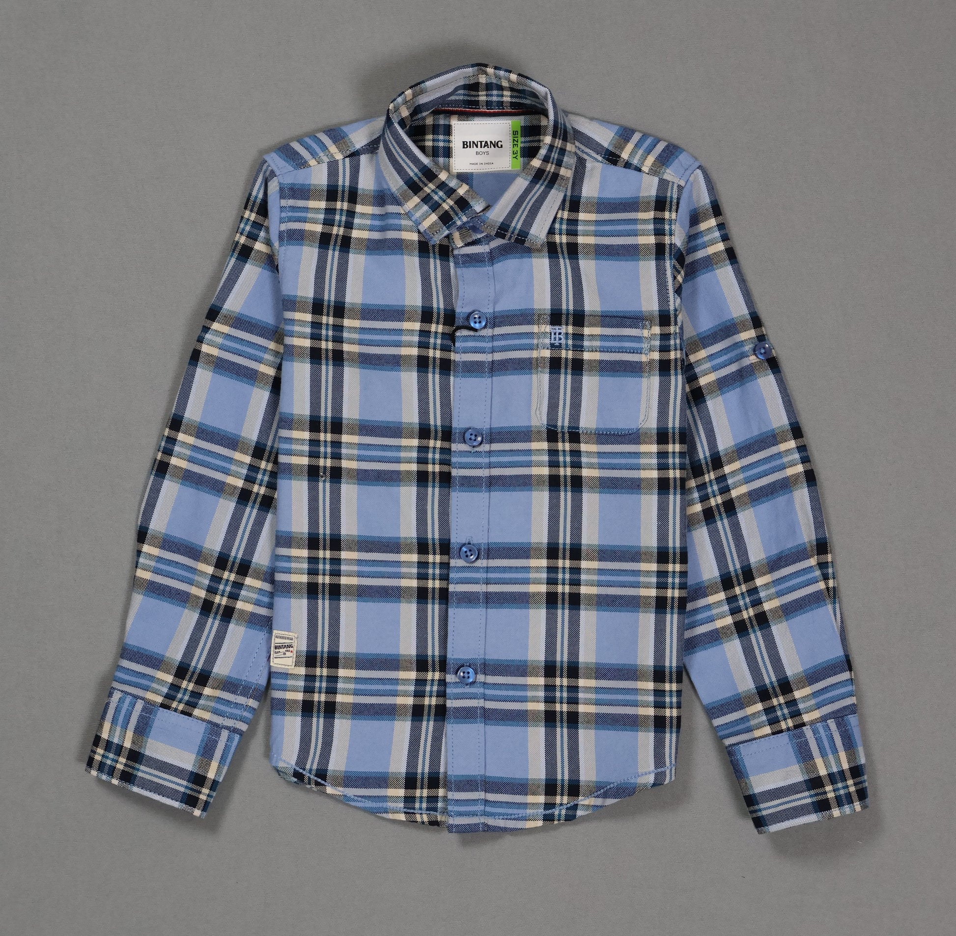 Blue and black plaid cotton kids shirt with long sleeves and front pocket on grey background