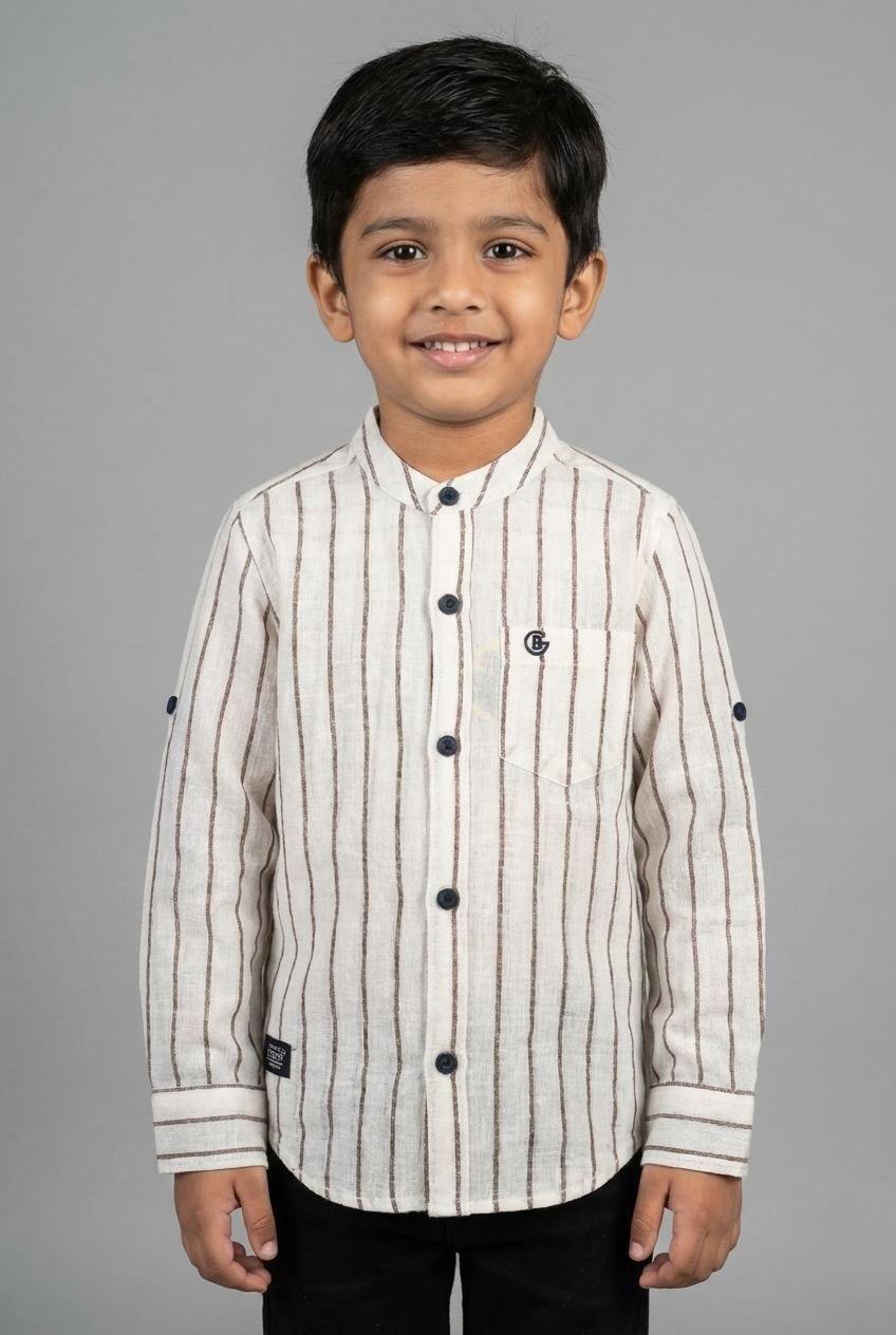 A young boy wearing a beige and brown vertical striped full-sleeve shirt from Fyst Fashion. The shirt features a modern mandarin collar, a front chest pocket, and dark contrast buttons. The sleeves are designed with roll-up tabs for a versatile look. The image shows a front view of the child smiling against a neutral grey background.