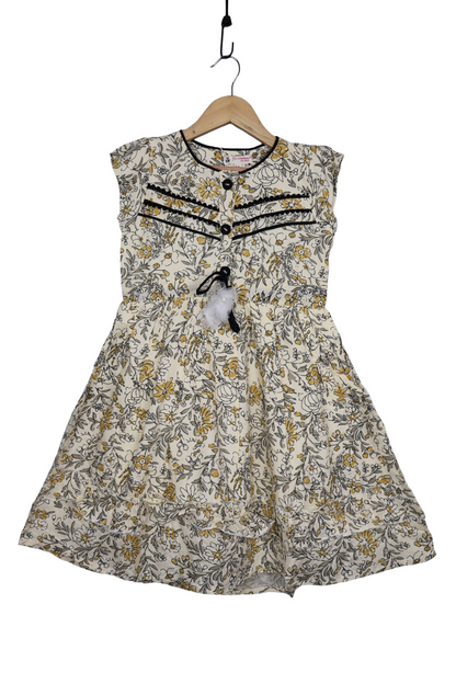 Girls cotton floral dress with yellow and black pattern and decorative buttons, hanging on hanger