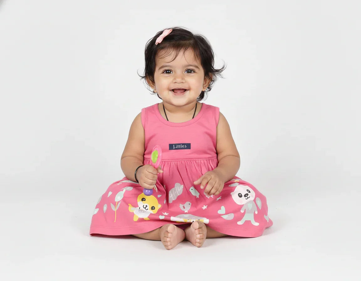 Baby wearing a pink dress with animal prints on a white background