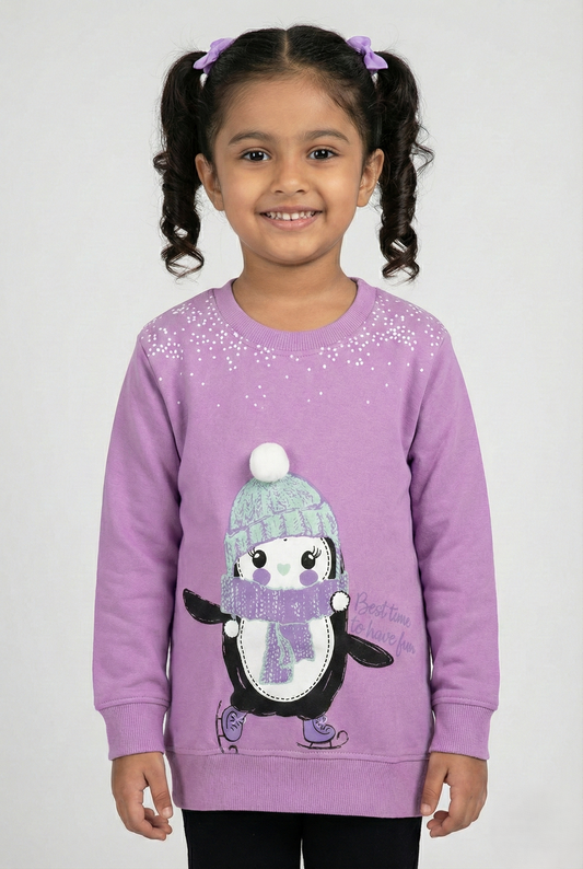Purple long-sleeve crewneck sweatshirt for girls. The center features a large graphic of a cute cartoon penguin ice skating, wearing a mint green knit hat with a white pom-pom and a purple scarf. White speckled snow details appear near the neckline, and the text 'Best time to have fun' is printed on the side